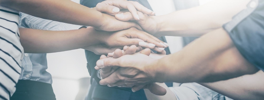 Image of coworkers putting their hands in together