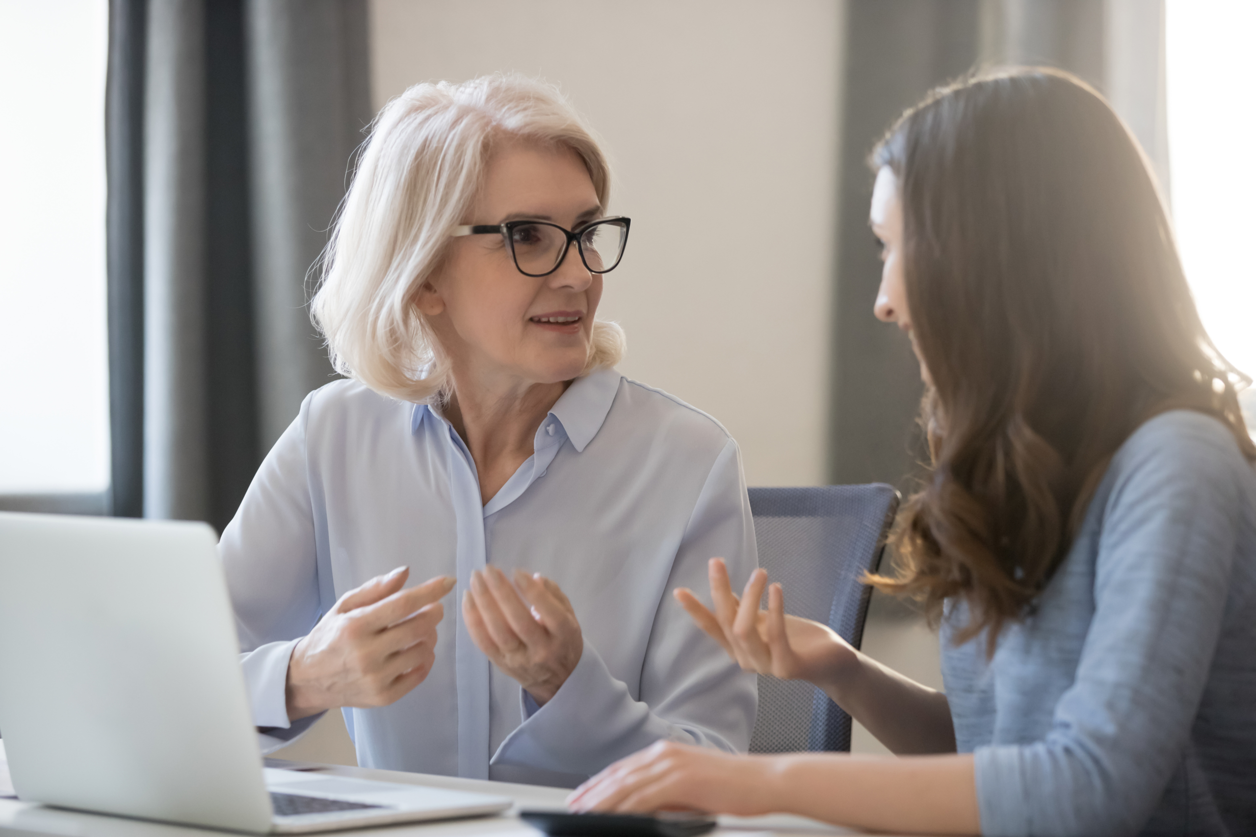 Two colleagues in a serious one-on-one conversation at a desk, representing harassment and discrimination prevention training