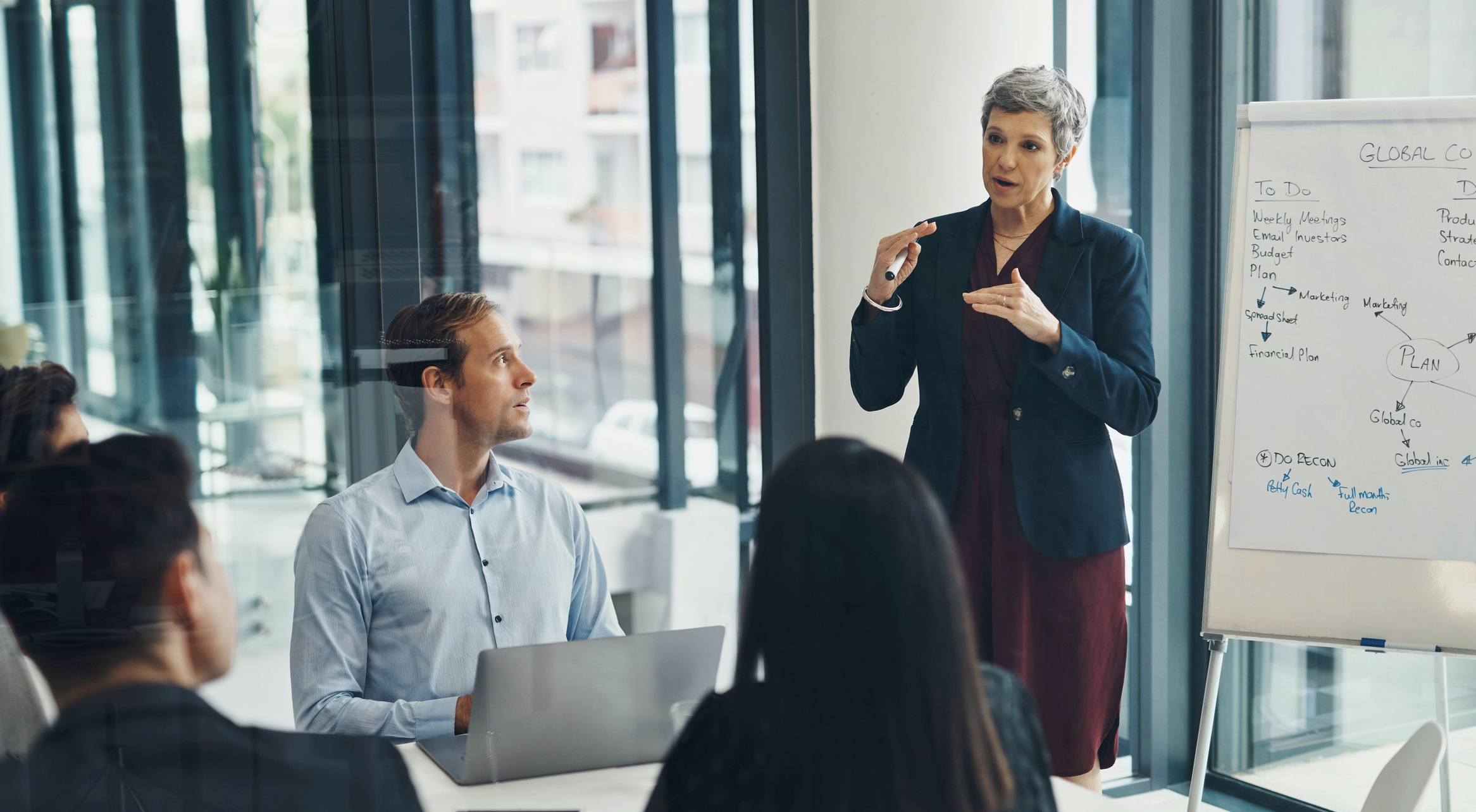 A leader presenting to a team in a meeting room, representing leadership and HR skills training